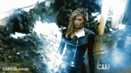A Woman In A Superhero Costume Is Standing In Front Of A Smokey Background . GIF