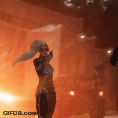 A Woman In A Superhero Outfit Is Standing In Front Of A Fire GIF