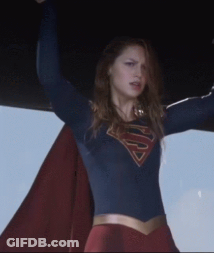 A Woman In A Superman Costume Holds Her Arms Up In The Air GIF