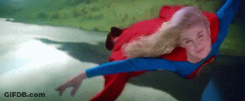 A Woman In A Superman Costume Is Flying Through The Air GIF
