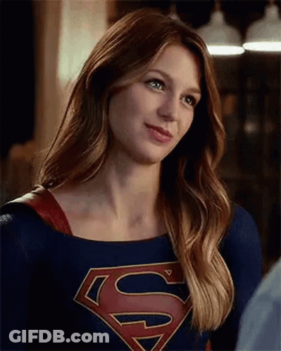 A Woman In A Superman Costume Is Smiling And Looking At A Man . GIF