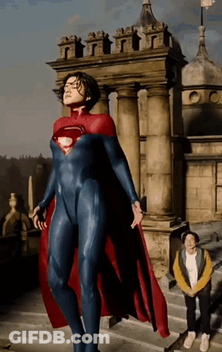 A Woman In A Superman Costume Is Standing In Front Of A Castle GIF