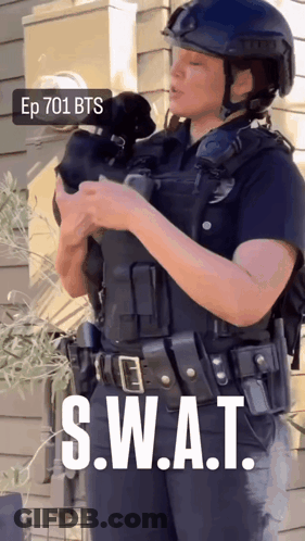 A Woman In A Swat Uniform Holds A Small Dog GIF