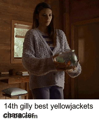 A Woman In A Sweater Is Holding A Fish In A Bowl GIF