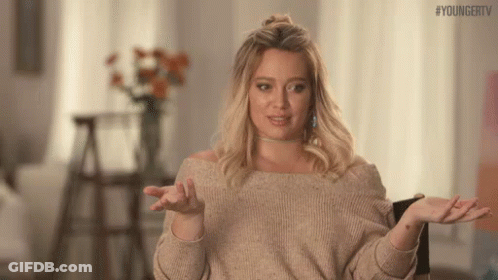A Woman In A Sweater Is Shrugging Her Shoulders And Making A Funny Face . GIF