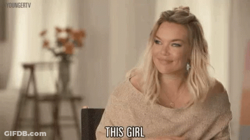 A Woman In A Sweater Is Sitting In A Chair And Smiling While Saying This Girl . GIF