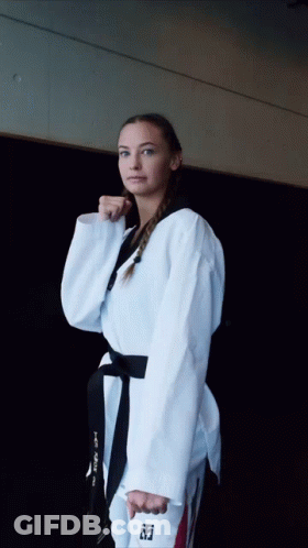 A Woman In A Taekwondo Uniform Holds A Black Belt With The Letter T On It GIF