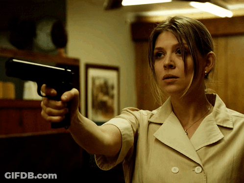 A Woman In A Tan Jacket Is Pointing A Gun GIF