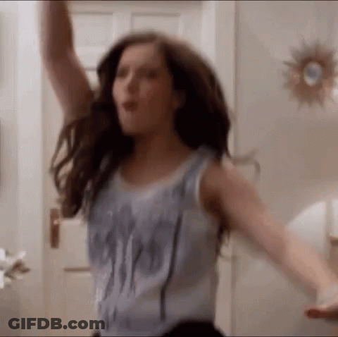 A Woman In A Tank Top Is Dancing With Her Arms Outstretched . GIF