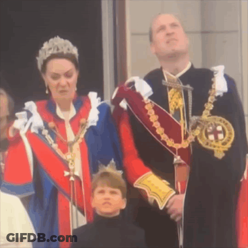 A Woman In A Tiara Is Standing Next To A Man In A Suit And A Boy In A Black Shirt . GIF