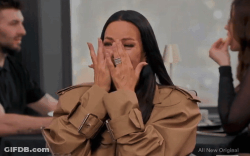 A Woman In A Trench Coat Covering Her Face With Her Hands And The Words All New Original On The Bottom GIF