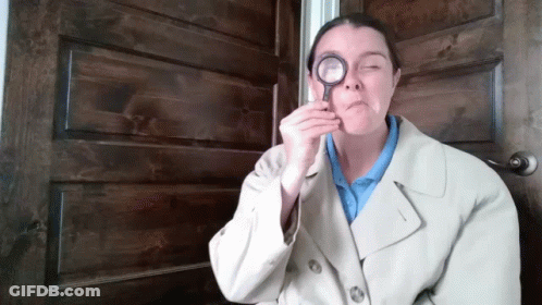 A Woman In A Trench Coat Holds A Magnifying Glass To Her Eye GIF
