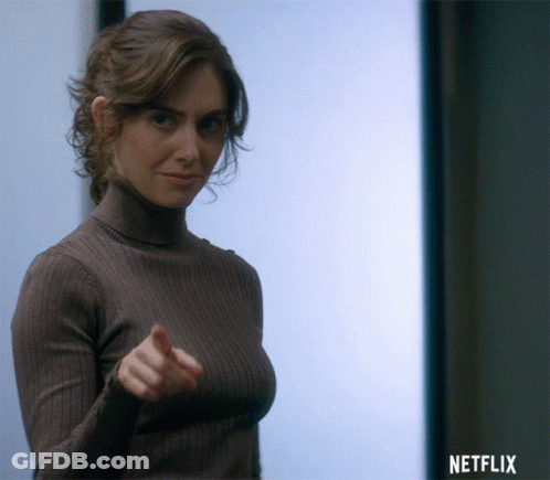 A Woman In A Turtleneck Sweater Is Pointing At The Camera With A Netflix Logo In The Background GIF