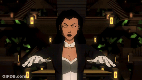 A Woman In A Tuxedo And White Gloves Stands With Her Arms Outstretched In A Dark Room GIF