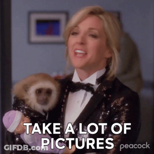 A Woman In A Tuxedo Is Holding A Baby Monkey And Says " Take A Lot Of Pictures " GIF