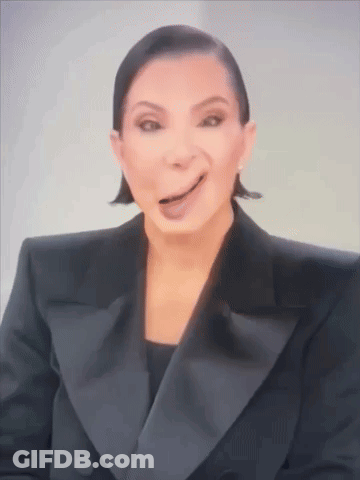 A Woman In A Tuxedo Is Making A Funny Face With Her Tongue Out . GIF