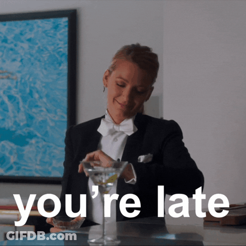 A Woman In A Tuxedo Is Pouring A Martini Into A Glass With The Words You 'Re Late Behind Her GIF