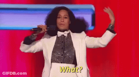 A Woman In A Tuxedo Is Singing Into A Microphone While Dancing On A Stage . GIF