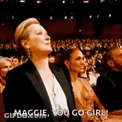 A Woman In A Tuxedo Is Sitting In Front Of A Crowd At A Awards Show . GIF