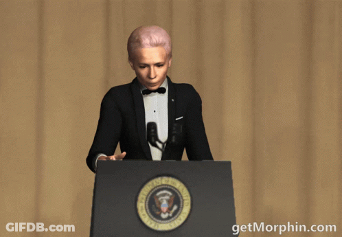 A Woman In A Tuxedo Stands At A Podium Holding A Microphone With The Words Getmorphin.com Written Below Her GIF