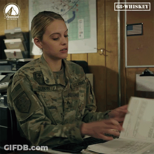 A Woman In A Us Army Uniform Sits At A Desk With Papers GIF
