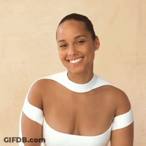 A Woman In A Very Plunging White Top Smiles GIF