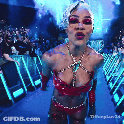 A Woman In A Very Revealing Outfit Is Standing In Front Of A Crowd With Tiffanyluv24 On The Bottom Right GIF