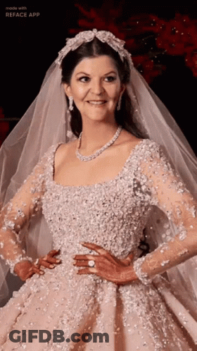 A Woman In A Wedding Dress And Veil Is Smiling GIF