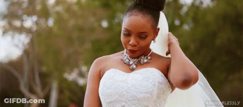 A Woman In A Wedding Dress And Veil Is Standing In Front Of A Forest . GIF