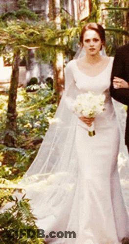 A Woman In A Wedding Dress Holding A Bouquet Of Flowers GIF