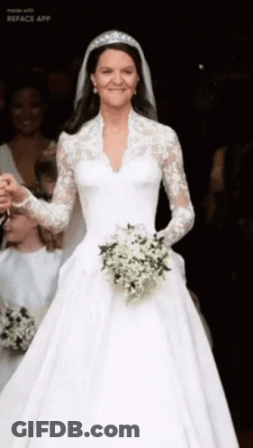 A Woman In A Wedding Dress Is Holding A Bouquet Of White Flowers GIF