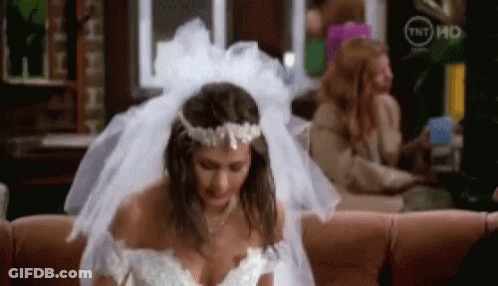 A Woman In A Wedding Dress Is Sitting On A Couch In A Living Room . GIF