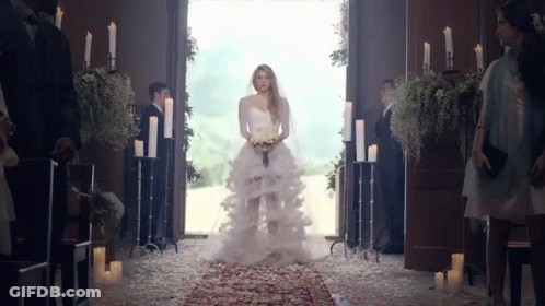 A Woman In A Wedding Dress Is Walking Down The Aisle In A Church GIF
