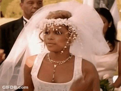 A Woman In A Wedding Dress Is Wearing A Veil And A Flower Crown . GIF