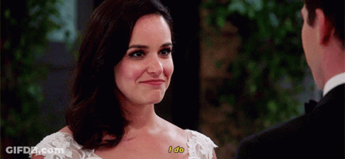 A Woman In A Wedding Dress Says I Do While Looking At A Man In A Suit . GIF