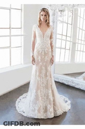 A Woman In A Wedding Dress Stands In Front Of A Mirror GIF