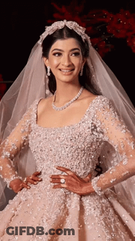 A Woman In A Wedding Dress With A Veil On Her Head Is Smiling GIF