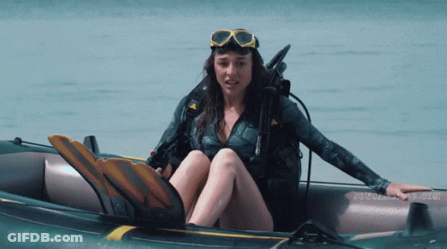A Woman In A Wet Suit Is Sitting In An Inflatable Boat With The Word Scuba On The Bottom GIF