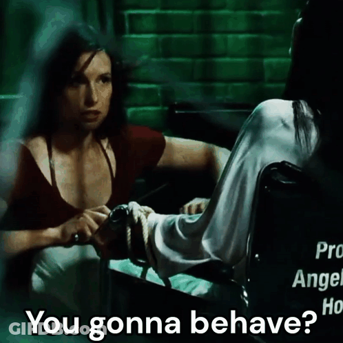A Woman In A Wheelchair Talks To Another Woman Who Is Tied Up GIF