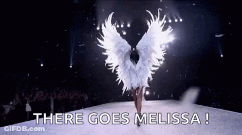 A Woman In A White Angel Costume Is Walking Down A Runway With The Words `` There Goes Melissa '' . GIF