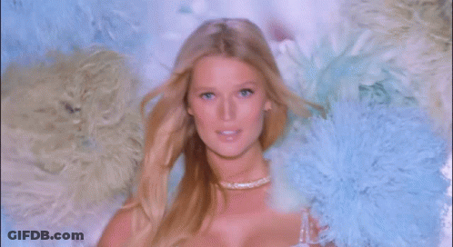 A Woman In A White Bra Is Surrounded By Feathers GIF
