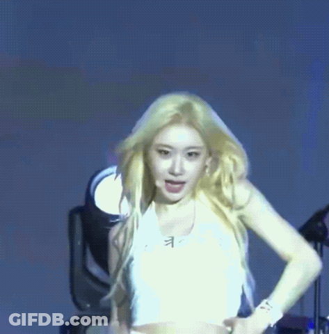 A Woman In A White Crop Top Is Dancing On A Stage . GIF