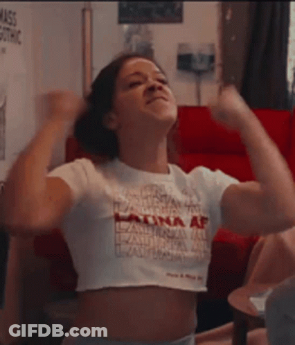 A Woman In A White Crop Top Is Flexing Her Muscles . GIF