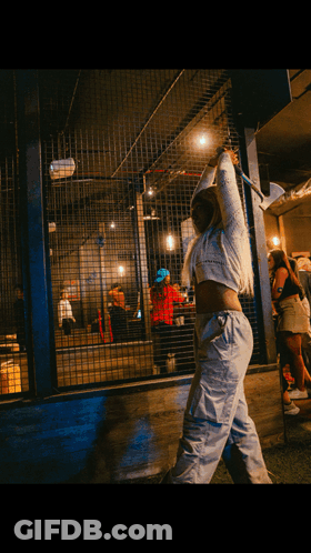 A Woman In A White Crop Top Is Holding An Axe Over Her Head GIF