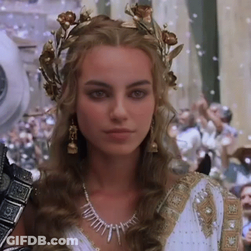 A Woman In A White Dress And A Gold Crown On Her Head . GIF