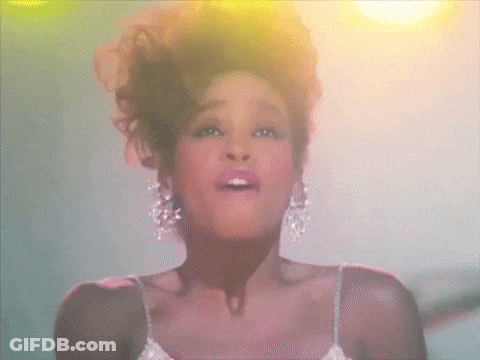 A Woman In A White Dress And Earrings Is Singing GIF