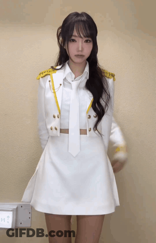 A Woman In A White Dress And Tie Is Standing In Front Of A Wall That Says Exit GIF