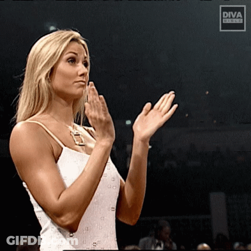A Woman In A White Dress Applauds In Front Of A Diva Screen GIF