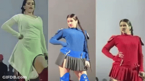 A Woman In A White Dress , Blue Sweater And Red Skirt Is Dancing On A Stage . GIF