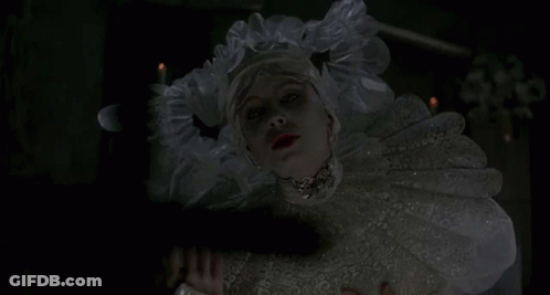 A Woman In A White Dress Holds A Cross In Front Of Her Face GIF